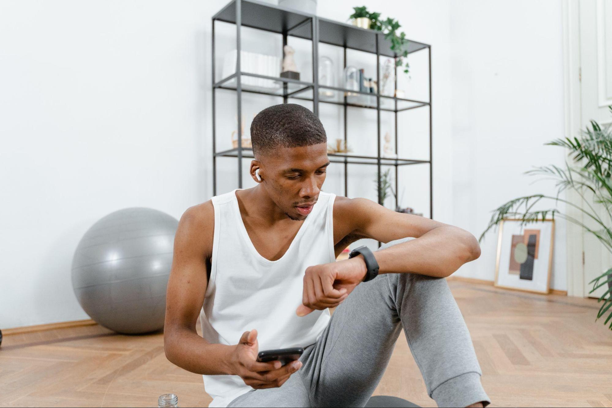 man looking at his watch while resting at the gym