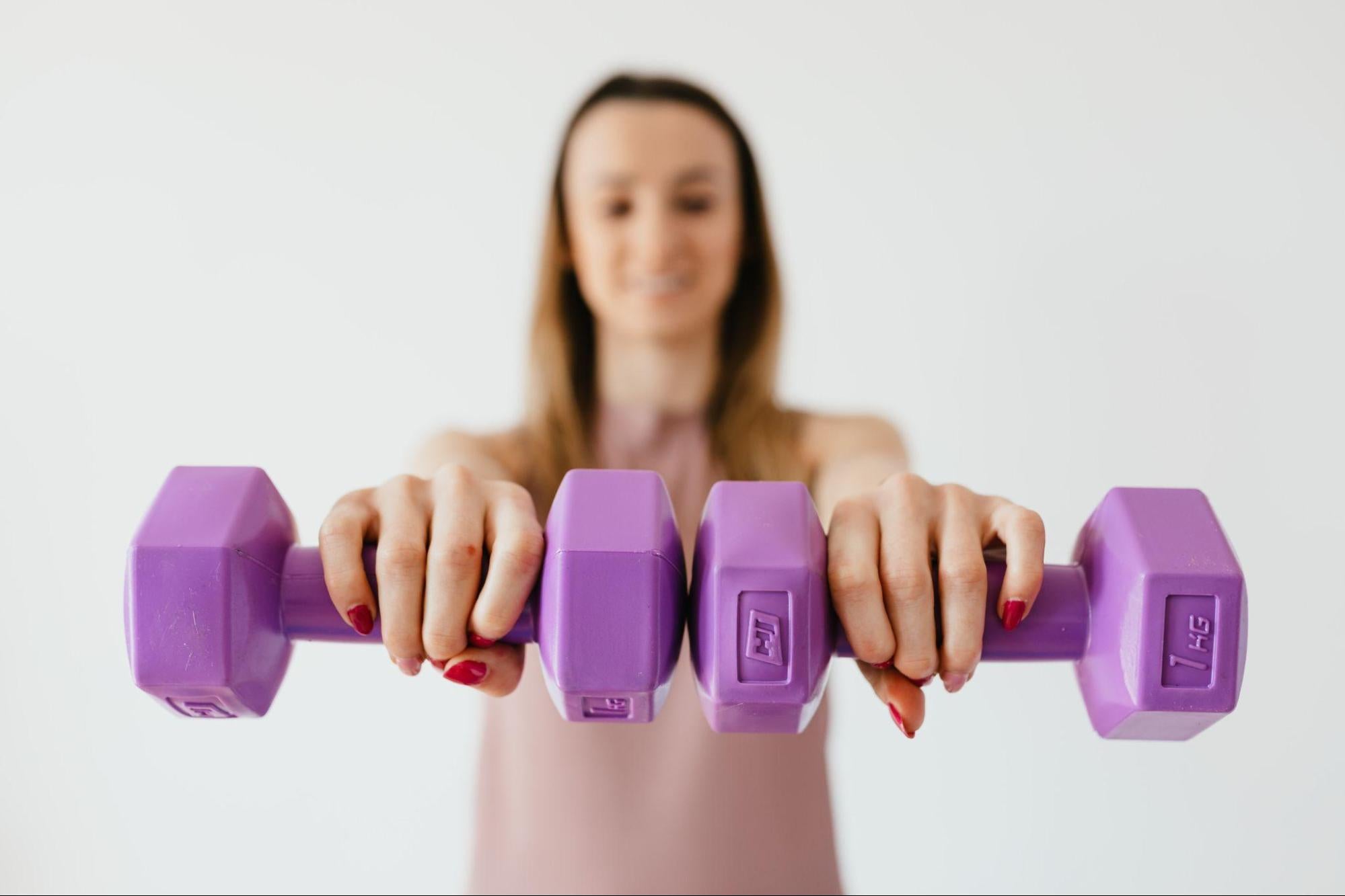 woman holding up two dumbbells