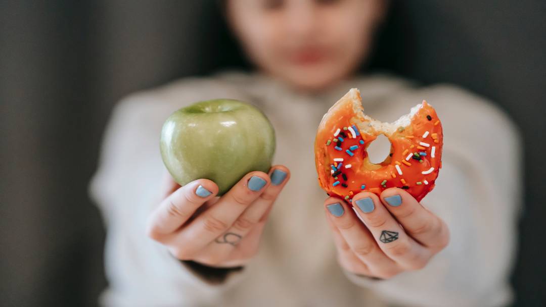 person holding apple and donut